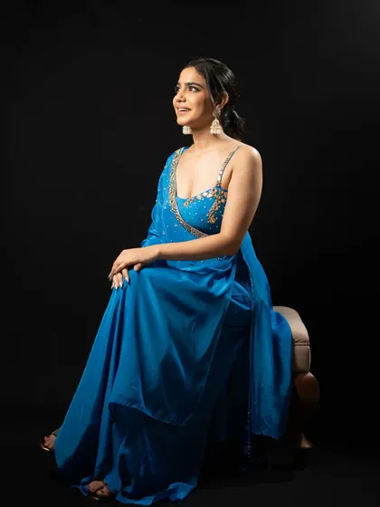 Modeling a vibrant blue Indo-Western outfit against a black studio background. The side slit and embellished top make it a stylish choice for a sangeet.