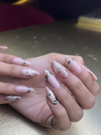 A soft and dreamy set with a touch of sparkle. These long, almond-shaped extensions have a sheer nude base, decorated with silver and gold glitter, stars, and delicate line work.