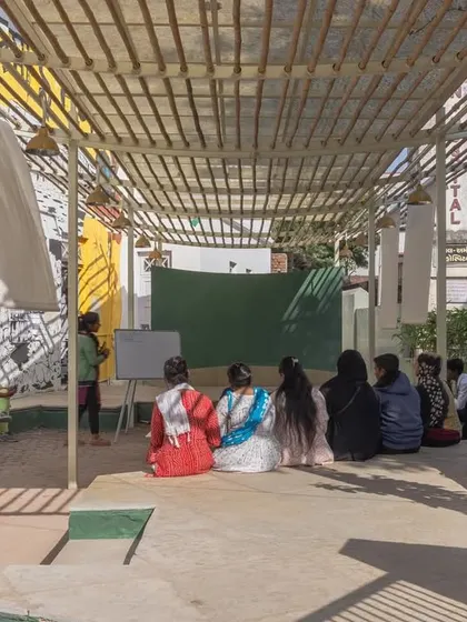 An educational session in progress at Basera. The space was designed to be a versatile platform, accommodating everything from vocational training to informal gatherings, all sheltered under a light-diffusing bamboo canopy.