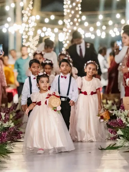 The little attendants make their way down the aisle. The decor, with its neat floral arrangements, provides a perfect frame for these adorable and cherished wedding moments.
