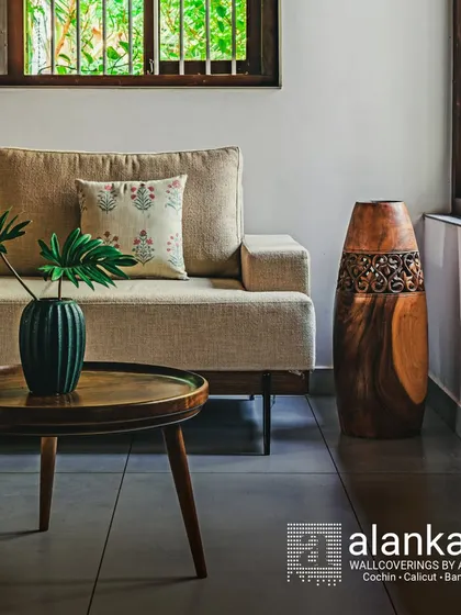 A classic sofa in a neutral beige fabric, perfect for a home that blends traditional and modern elements. The piece is complemented by a carved wooden vase and a mid-century modern coffee table.