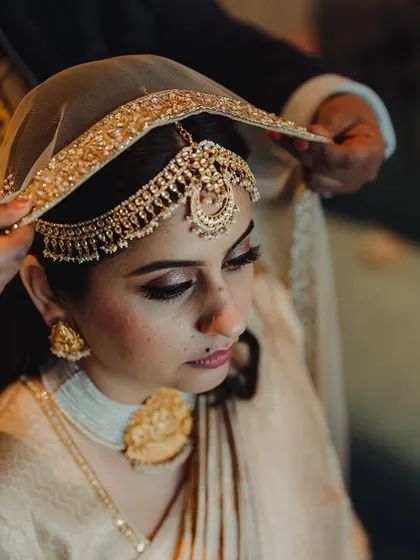 A close-up of the bride getting ready, with a helping hand adjusting her intricate headpiece.