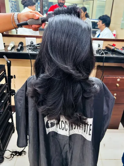 A student is guided on how to use a round brush to achieve the perfect voluminous blow-dry on an advanced layered cut.