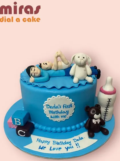 A cake celebrating "Dada's first Birthday with me." This sweet blue cake shows a father and baby relaxing together, surrounded by toys and a milk bottle, marking a precious shared milestone.