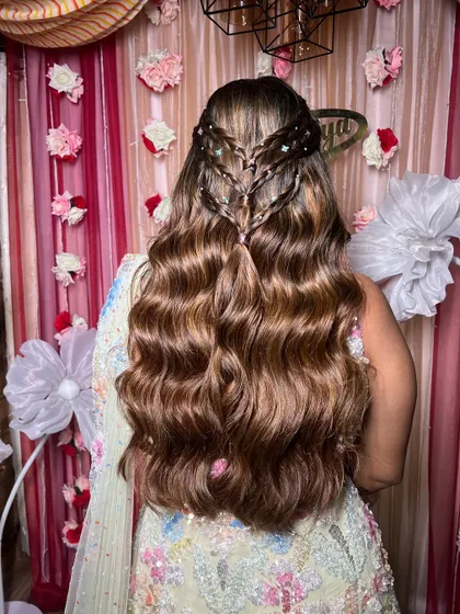 An intricate and modern hairstyle for a Sangeet or reception. This look features a beautiful braided detail on top with long, flowing waves.