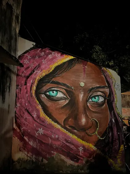 A powerful mural of a woman with striking blue eyes, her face partially covered by a sari, found on a wall in Pushkar.