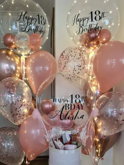 Celebrating an 18th birthday calls for something special. Here you can see our hot air balloon hamper alongside matching helium bunches, all in a beautiful rose gold theme with custom "Happy 18th Birthday" text.