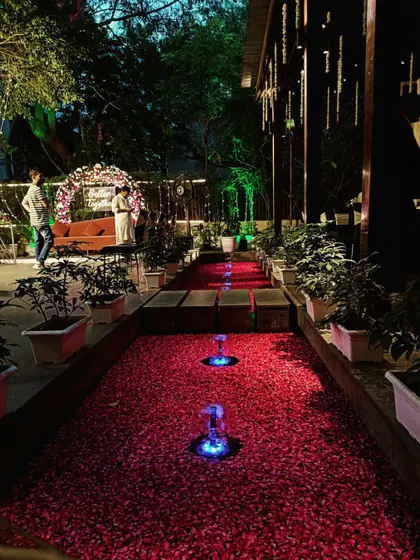 A beautiful evening setup with a water channel filled with red rose petals, leading to a romantic floral arch.