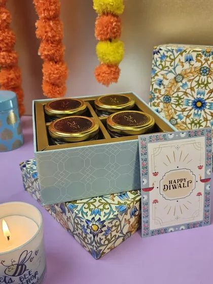 A premium Diwali hamper featuring four jars of dry fruits and a custom "Happy Diwali" card, all in a beautifully designed box.