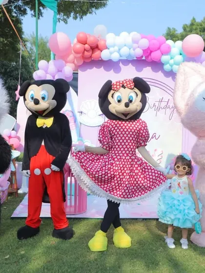 A great group shot of the birthday girl with all the character mascots. The outdoor setting and colorful decor create a perfect backdrop for a fun photo.