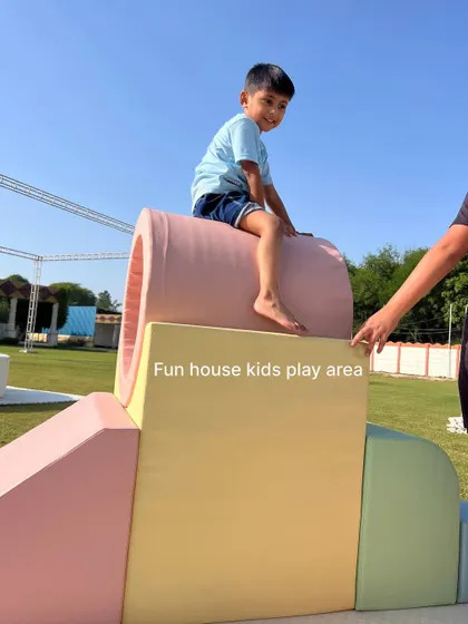 A child sitting atop the pastel tunnel, showcasing the sturdy construction of our soft play equipment.