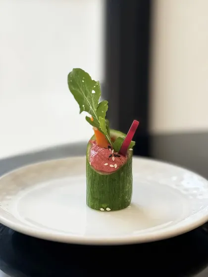 A refreshing and healthy appetiser. Our Cucumber Beetroot Bouquet features a hollowed-out cucumber filled with vibrant beetroot hummus and crisp vegetable sticks, resembling a small floral arrangement.