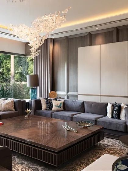 The floral-backed chairs and lush green upholstery bring a touch of nature indoors, while the earthy tones of white, grey, and brown connect the interiors with the vibrant outdoors.