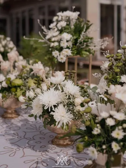 Beautiful white chrysanthemum arrangements in ornate gold bowls, used as part of the table centerpieces, adding texture and elegance.