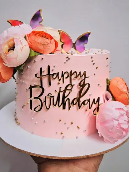 Pretty peachy! A beautiful rasmalai cake with peach-toned peonies and butterfly accents, perfect for a sophisticated birthday.