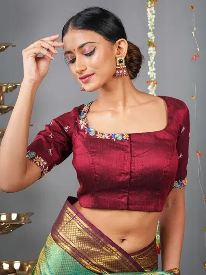 This maroon blouse with colorful embroidery on the neckline and sleeves is paired with large, multi-colored earrings.