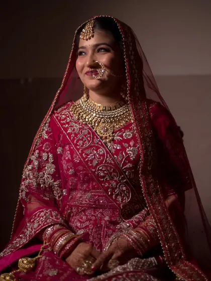A stunning portrait of the bride, Shweta, in her magnificent red bridal lehenga, captured in soft, dramatic lighting.