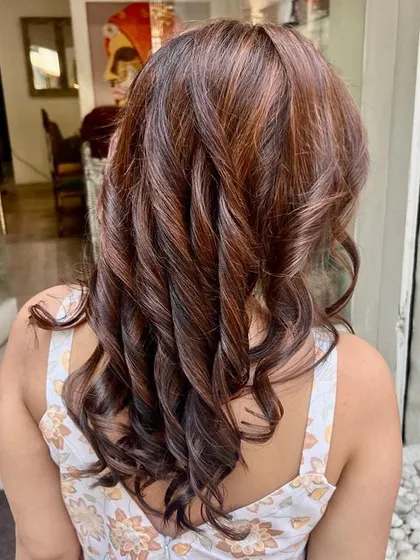A beautiful color transformation from black to hazelnut brown highlights. This look is perfect for anyone wanting to lighten up their dark hair without a drastic change, adding warmth and dimension with a soft, curled finish.