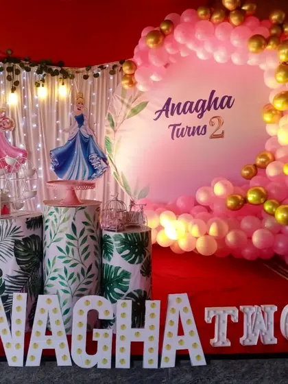 A lovely Disney Princess theme for Anagha's second birthday. The design uses a circular backdrop, a pink and gold balloon arch, and pedestals with tropical leaf prints for a unique touch.