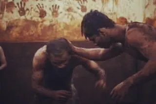 An old, powerful image showing the Guru-Shishya tradition. A senior wrestler guides a junior, passing down knowledge and blessings in the 'lal mati', a practice we cherish.