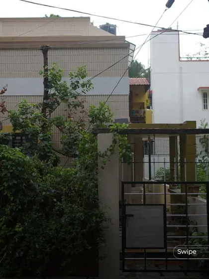 The entrance to the V S Sreedhara Residence, nestled behind lush greenery that provides privacy and a connection to nature.