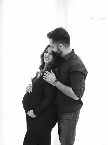 Sometimes, the quiet moments are the most powerful. This black and white couple's portrait uses high-contrast lighting to focus purely on the intimate connection and shared joy between the parents-to-be.