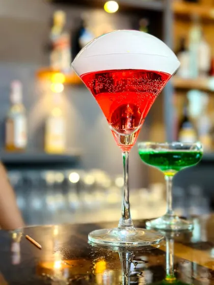 A close-up of a vibrant red cocktail with a smoke bubble, showcasing the visual appeal of our molecular drinks.