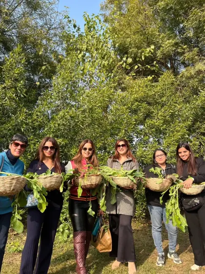 A group of ladies smiling for the camera, each holding a basket of their harvested vegetables.