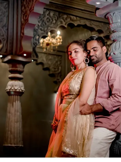 A romantic portrait of the couple in a warm, ambient setting with traditional architecture.