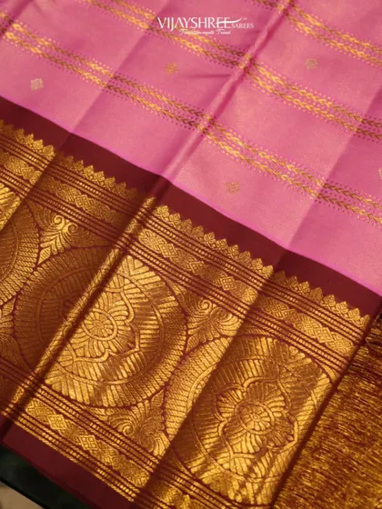 A close-up of the wide gold border on the pink Kanjivaram, showcasing the intricate floral patterns woven within the large chakram motifs.