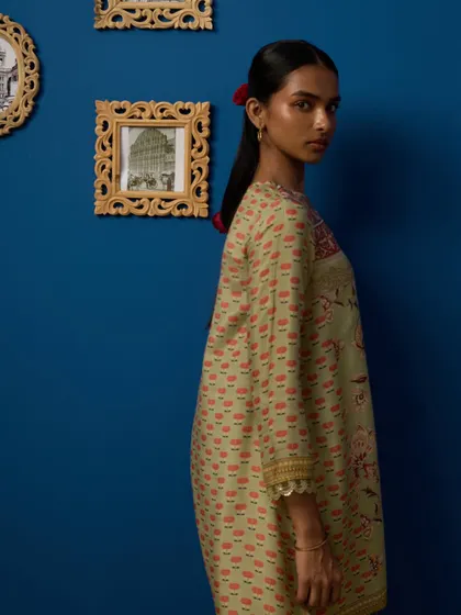 A campaign shot for a slow fashion brand. The rich blue wall and traditional frames create a beautiful, culturally rich backdrop for the simple, elegant kurta.