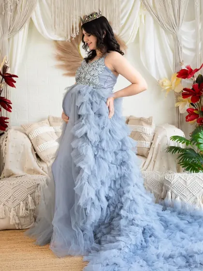 A side profile of a beautiful light blue gown with a long, ruffled train. This shot highlights the texture and flow of the dress in our bright studio setting.