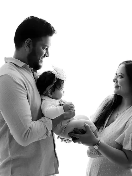 A classic black and white family portrait with a newborn. The high-key lighting creates a clean and timeless look, focusing on the family's interaction with their new baby.