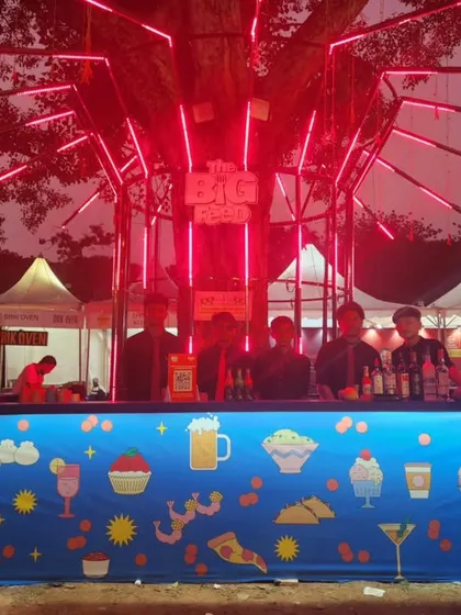 We are equipped to handle the high energy and volume of large public events and festivals. This photo shows our bar setup at 'The Big Pitcher' food festival, serving a large crowd under a custom-lit tree structure.
