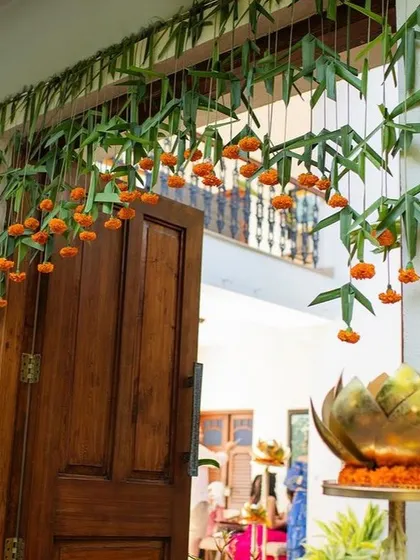 A traditional door entrance decorated with hanging marigolds and mango leaves.