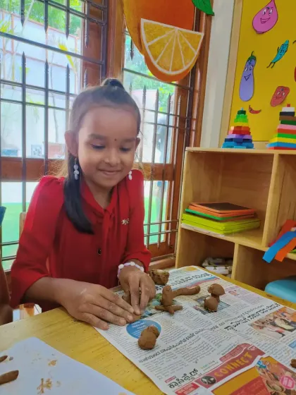 A smiling camper works on her clay creations, surrounded by colorful classroom materials. Our environment is designed to inspire creativity at every turn.