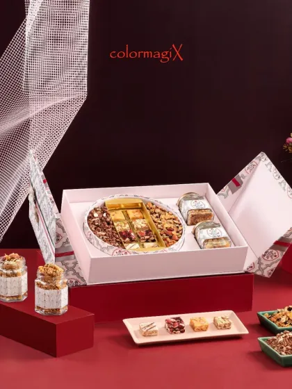 A sophisticated pink and grey patterned box filled with a variety of dry fruits and nuts. The circular platter inside is a unique design element that sets this hamper apart.