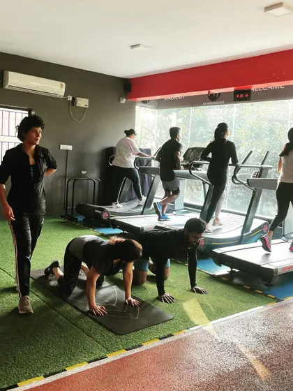 A busy gym scene with clients on treadmills and others doing floor exercises, showing the dynamic flow of a group session.