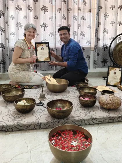 A student receives her certificate after an intensive sound healing course, surrounded by the tools of the practice.