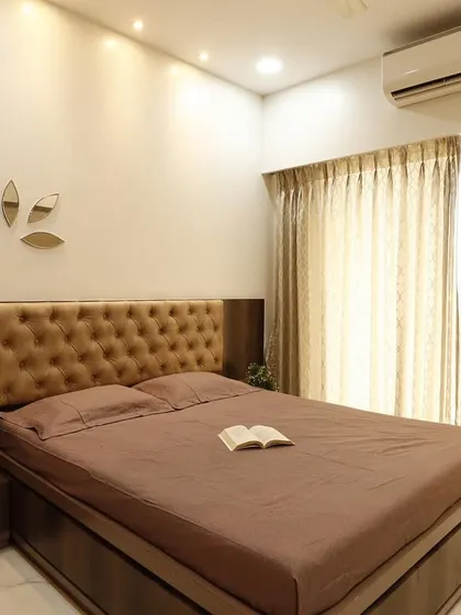 The bed area of the guest room, featuring a simple, clean design with a tufted headboard and decorative mirror accents on the wall. The focus is on creating a comfortable and uncluttered space for guests.