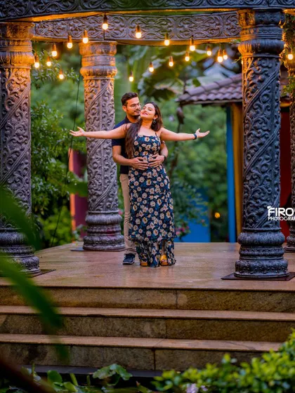 A joyful, "Titanic" inspired pose at the stone structure, lit by hanging bulbs. This fun and romantic shot captures the couple's playful energy.