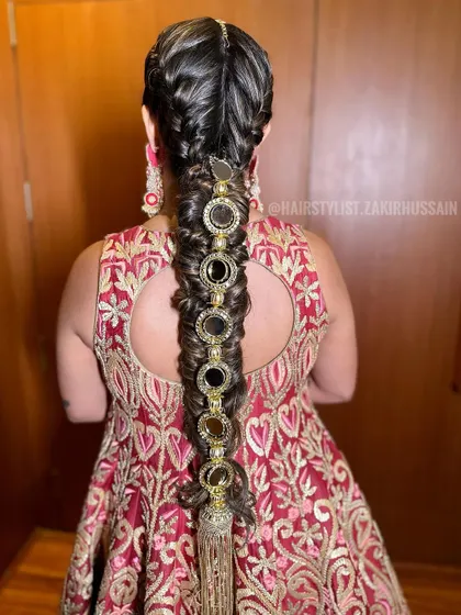 This is a modern take on a traditional braid, featuring a fishtail braid adorned with large, circular mirror accessories. It's a bold and unique hairstyle for a confident bride.