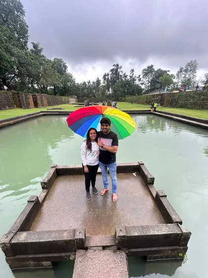 A couple with a colorful umbrella at a temple pond, a serene moment during the Kodachadri trip.