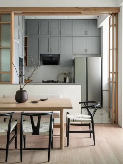 This view shows the open kitchen from the dining area. The versatile wooden sliding doors with fluted glass allow for a perfect harmony between an open and closed kitchen experience, depending on the occasion.