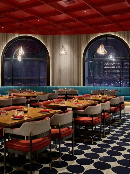 The main dining floor at Foo at night, where the city lights from the arched windows become a backdrop to the warm interior lighting and bold color scheme.