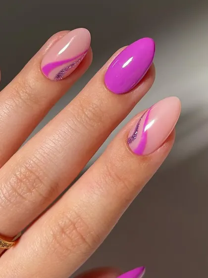 A pop of color with a modern twist. This design combines solid purple nails with accent nails that feature a purple swirl and a hint of glitter on a sheer base.