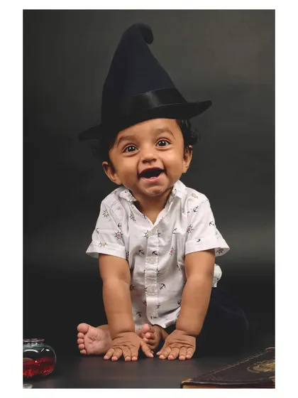 A happy wizard in the making! This baby's bright smile and playful pose make for a heartwarming and memorable themed portrait.