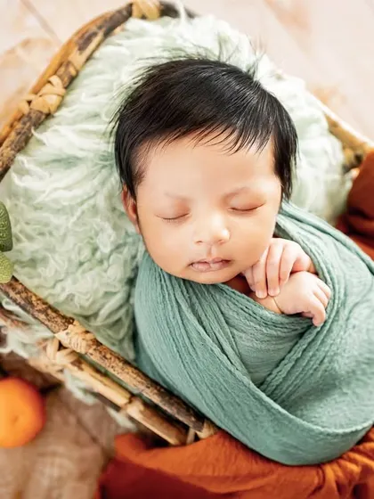 A pop of color with this citrus-themed newborn setup. Using natural elements like these small oranges adds a fresh and unique touch to the classic basket pose.