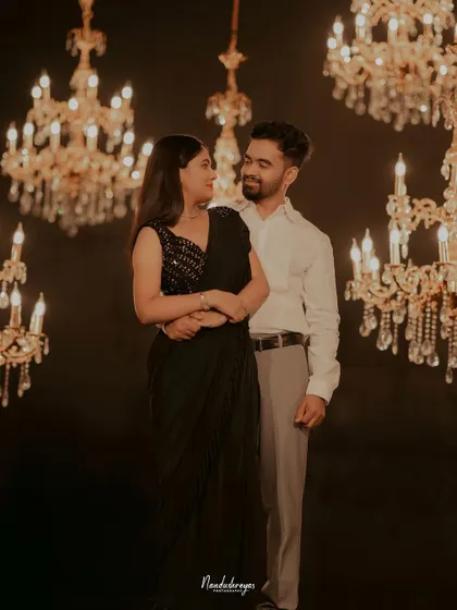 A romantic portrait of a couple surrounded by glowing chandeliers, creating a warm and opulent atmosphere.