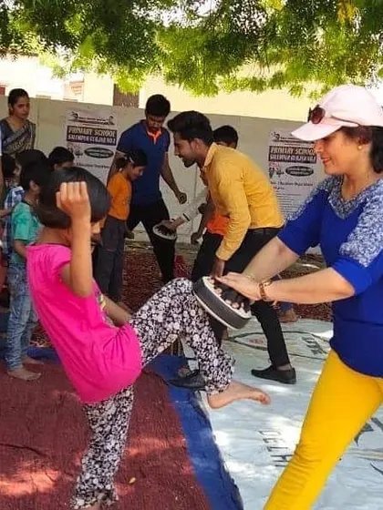 A young girl practices her kicks on a pad during our community outreach program. We teach practical skills in a supportive environment.